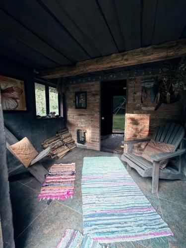 a room with a fireplace and two rugs in a cabin at Zariņmājas Mistērija in Ceļarāji