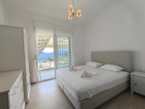 a white bedroom with a bed and a large window at Апартаменты Елена in Nea Peramos