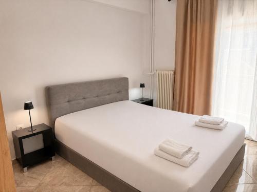 a bedroom with a white bed with two towels on it at Central Park Chíos in Chios