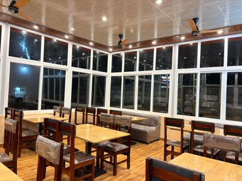 a dining room with tables and chairs and windows at Seabreeze Village Resort and Restaurant in Gokarn