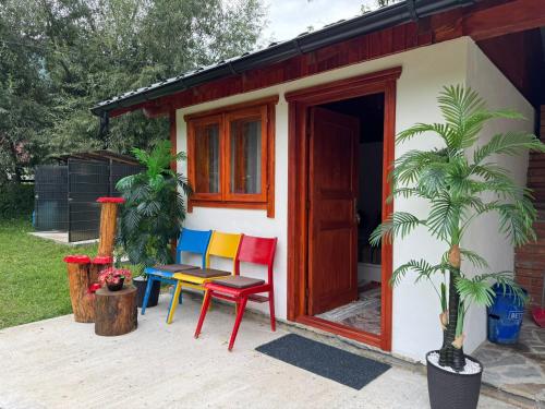 a small house with colorful chairs and a table at Casuta -Dor de Munte -Ceahlau in Bistricioara
