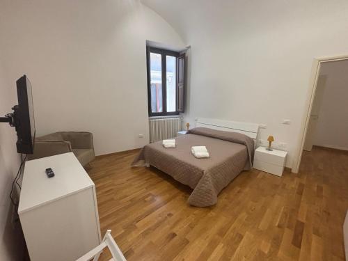 a bedroom with a bed and a flat screen tv at La Dimora del Duomo in LʼAquila