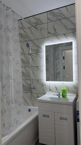a bathroom with a sink and a mirror and a tub at АК Кеме in Osh