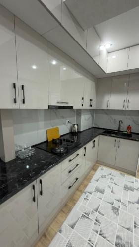 a kitchen with white cabinets and a black counter top at АК Кеме in Osh