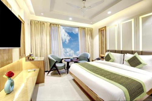 a hotel room with a bed and a desk and a television at Hotel Shambhu Narayan G K Group Varanashi in Varanasi