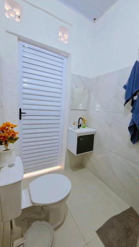 a white bathroom with a toilet and a sink at Home Hostel Maceió in Maceió