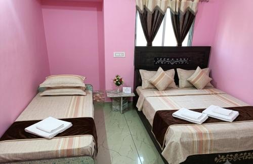 two beds in a room with pink walls at Shiva Homestay Dwarka in Dwarka