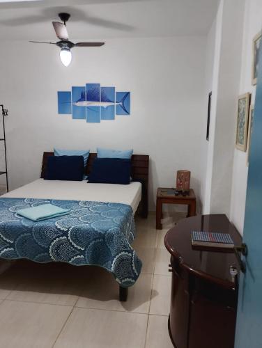 a bedroom with a bed with blue pillows and a table at Vereda da Lagoa in Niterói