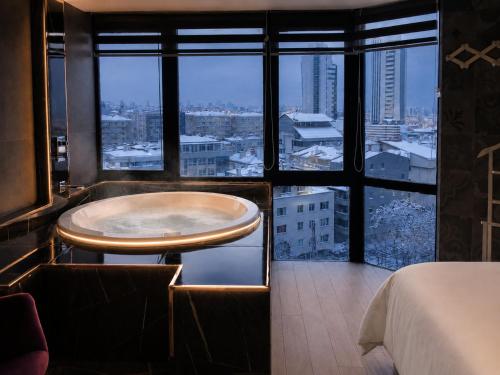 a room with a tub in the middle of a room with windows at Reco Luxury Suite in Kavaklıdere