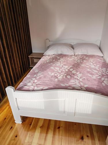 a white bed with a pink comforter on it at Apartman Ploče in Bajina Bašta