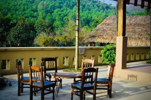 a table and chairs on a patio with a view of a mountain at Bản Bọc Chăm Chứng in Làng Vach
