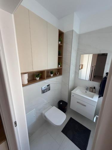 a white bathroom with a toilet and a sink at Apartament in Ploiesti in Ploieşti