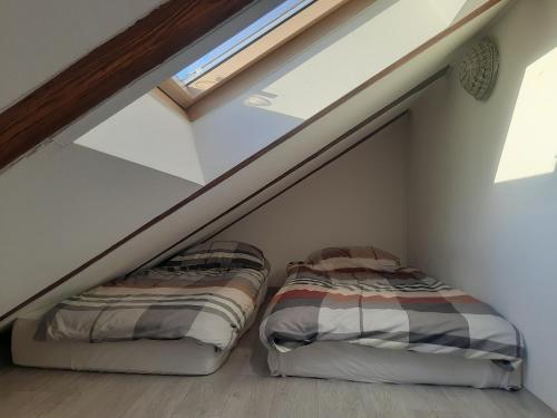 two beds in a attic bedroom with a window at Loft przy Starym Mieście in Jarosław