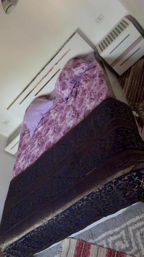 a bed with a purple comforter and a book at Casuta -Dor de Munte -Ceahlau in Bistricioara