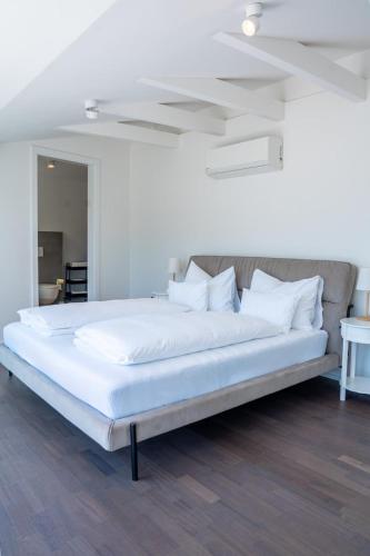 a large bed with white sheets and white pillows at DAS ANTON - Penthouse mit Seeblick und kostenloser Garage in Gmunden