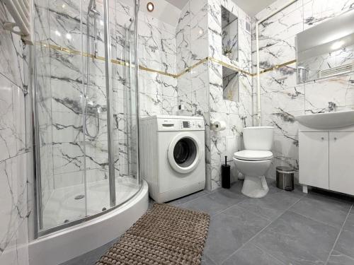 a bathroom with a shower toilet and a washing machine at Apartament przy Kauli in Inowrocław