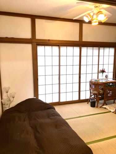 a room with a bed and a table and windows at The Village House 1 in Hadano