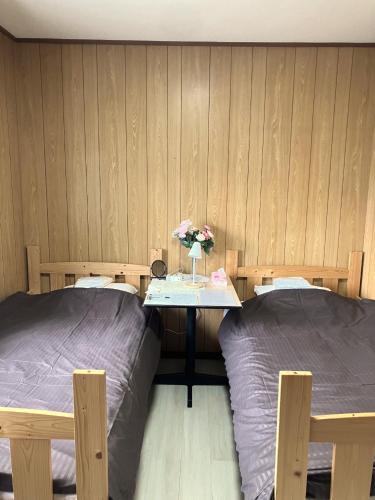 a room with two beds and a table with flowers at The Village House 1 in Hadano