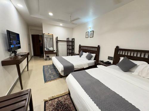 a hotel room with two beds and a flat screen tv at Hotel Misty Meadows by Vanyum in Pachmarhī