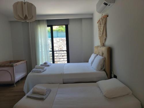 two beds in a room with a window at Villa Ada Bohème in Muğla