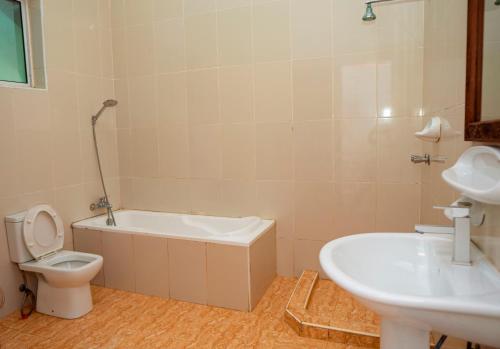 a bathroom with a tub and a toilet and a sink at Visitors Inn Zanzibar in Jambiani