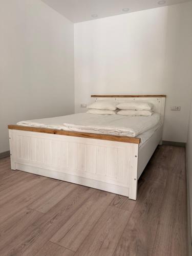 a bed with a wooden frame in a room at Crown Apartment Secret Corner in Ukmergė