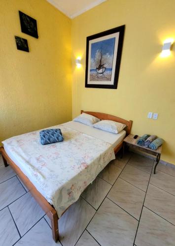 a bedroom with a bed in a yellow room at Pousada Nova Onda in Paranaguá