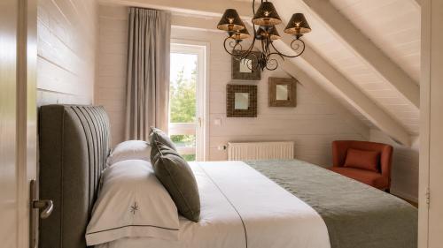 a bedroom with a bed and a chair and a window at Valentina Lodge in Durbuy