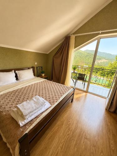 a bedroom with a large bed and a large window at cottage in tsemi (Borjomi) in Borjomi