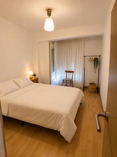 a bedroom with a large white bed and a chair at Apt Puerto Burriana in Burriana
