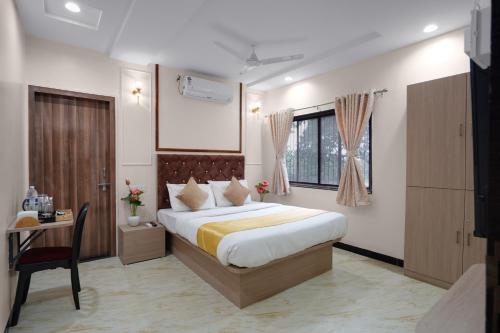 a bedroom with a bed and a desk and a window at Hotel Royal Comforts in Pune
