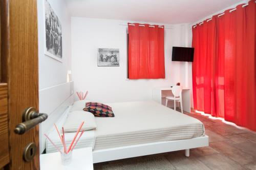 a bedroom with red curtains and a white bed at Moresco Agriturismo in Moresco
