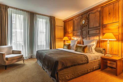 a bedroom with a large bed and a chair at Hôtel Lion d'Or 1774 - Châteaux de la Loire in Romorantin