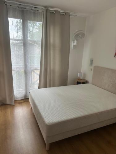a bedroom with a white bed with a window at Villa de l Eyre in Salles