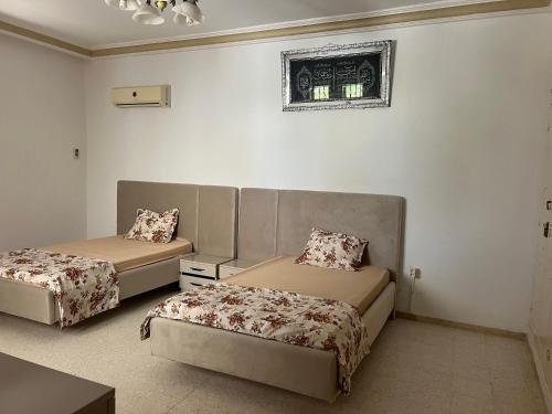 a bedroom with two beds and a table and a window at La villa jasmin in Al Maqārisah