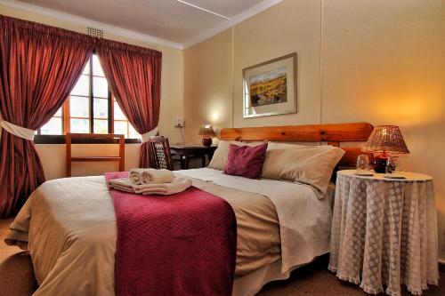 a bedroom with a large bed with a red table at Zoete Inval Travelers Lodge-Backpacker Loft in Hermanus