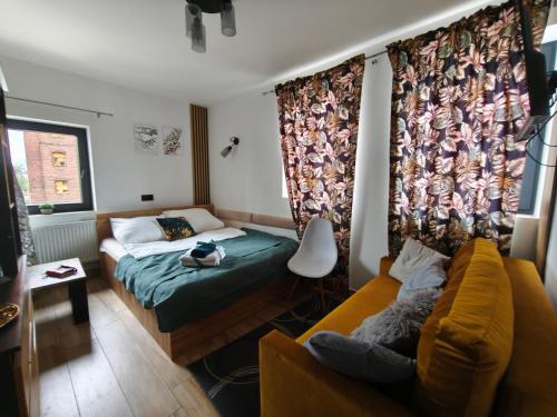 a small bedroom with a bed and a couch at Apartamenty RETRO FV in Koszalin
