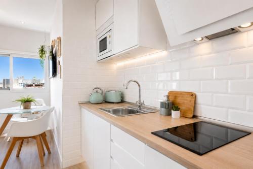 a white kitchen with a sink and a table at New Central Studio Torremolinos in Torremolinos