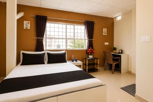 a bedroom with a bed and a desk and a window at Leo Stays in Bangalore