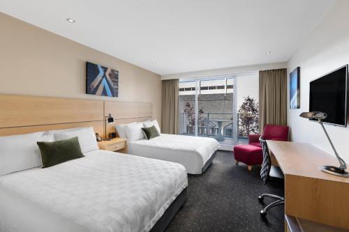 a hotel room with two beds and a desk at Crowne Plaza Queenstown by IHG in Queenstown