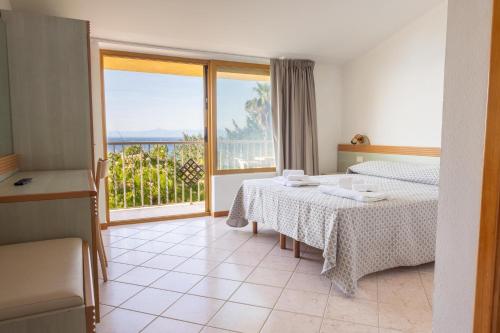 a hotel room with two beds and a balcony at Cala Petrosa Resort in Parghelia