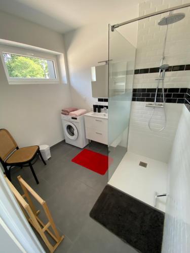 a bathroom with a glass shower and a washing machine at La grange du clos in Angiens