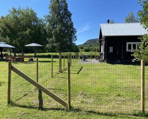 a fence in front of a field with a building at Villa Ragunda in Hammarstrand