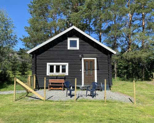 a black cabin with a table and chairs in front of it at Villa Ragunda in Hammarstrand