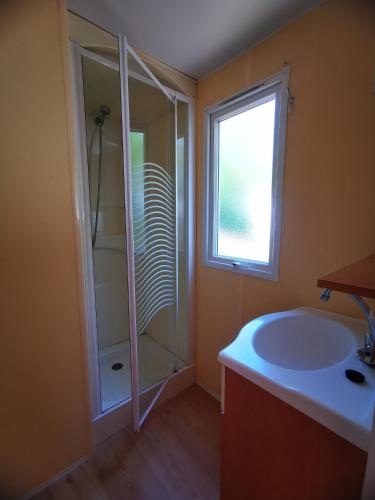 a bathroom with a shower and a sink and a window at Camping les sables in Aytré