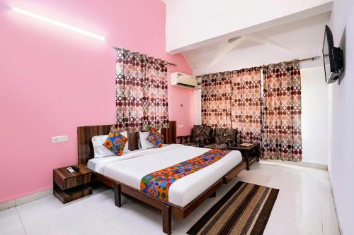 a bedroom with a bed and a pink wall at Triple Beach Guest House in Benaulim