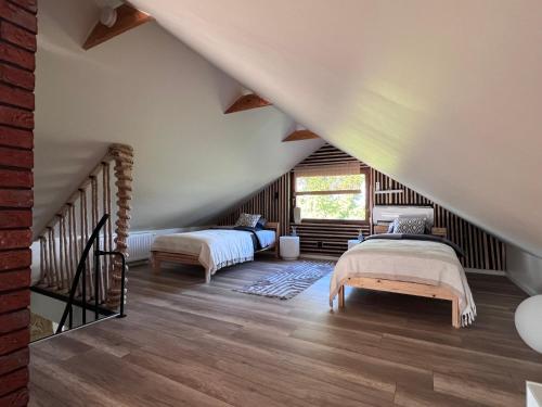 a attic bedroom with two beds and a staircase at Dom Na Wsi z Balią Ogrodową-Jacuzzi in Mierzwin Duży