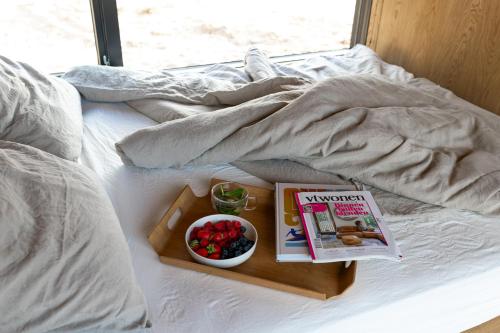 a tray with a book and a bowl of fruit on a bed at Eco by Nature - De Stilte - in Heythuysen