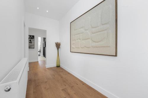 a hallway with white walls and a large picture on the wall at Private Double Room in Spacious House with Garden in Blackrod