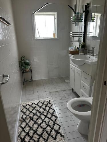 a white bathroom with a toilet and a sink at Charmigt hus uthyres in Holsljunga
